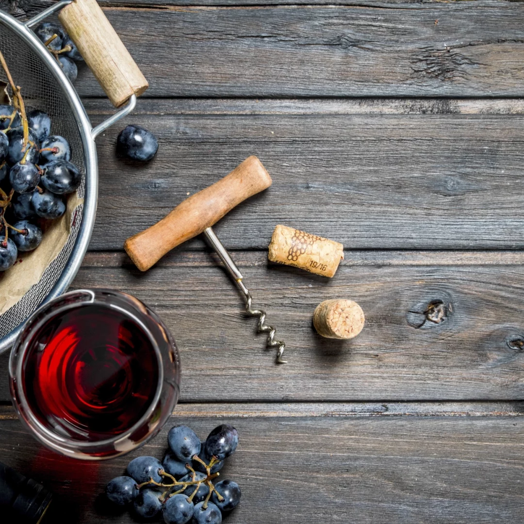 Vaso de vino, botella de vino y uvas sobre una mesa de madera.